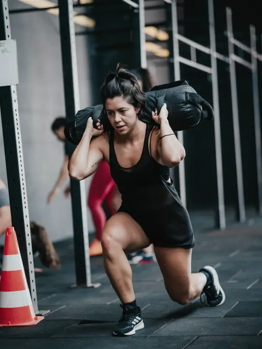 Atleta com sandbag em treinamento híbrido na Kapela Gym